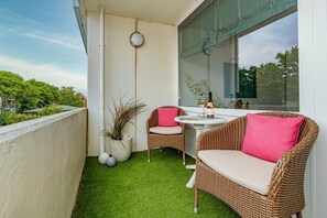 A balcony with artificial grass, wicker furniture, and a table with a bottle and glasses. - Lieblingsplatz - Comfortable vacation apartment Lieblingsplatz with balcony and (Sylt)
