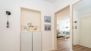 Ein Flur mit einem weißen Kleiderschrank, einem Spiegel und gerahmten Bildern an der Wand.