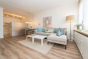 Un salon moderne comprenant un canapé, une table basse et un coin repas avec des chaises et une table.
