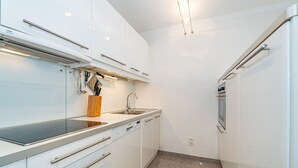 Eine kleine Küche mit weißen Schränken, einer Edelstahl-Spüle und einem eingebauten Backofen.