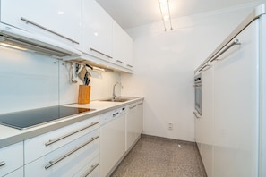 A compact kitchen with white cabinets, a stainless steel sink, and a built-in oven. - Lieblingsplatz - Comfortable vacation apartment Lieblingsplatz with balcony and (Sylt)