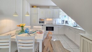 Een moderne keuken met witte kasten, een eettafel met stoelen en een bank.