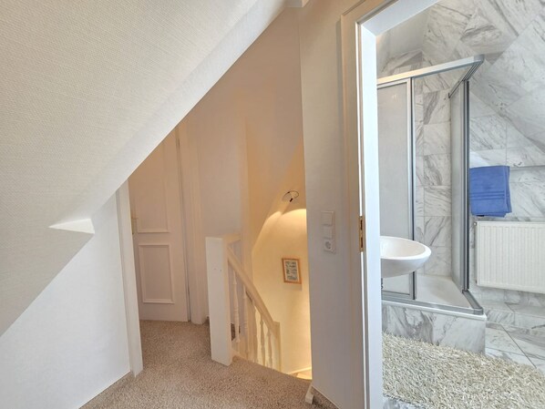 A bathroom with a marble sink and a glass shower enclosure.