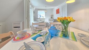 Een eetgedeelte met een tafel gedekt voor twee personen, een blauwe theepot en een vaas tulpen.