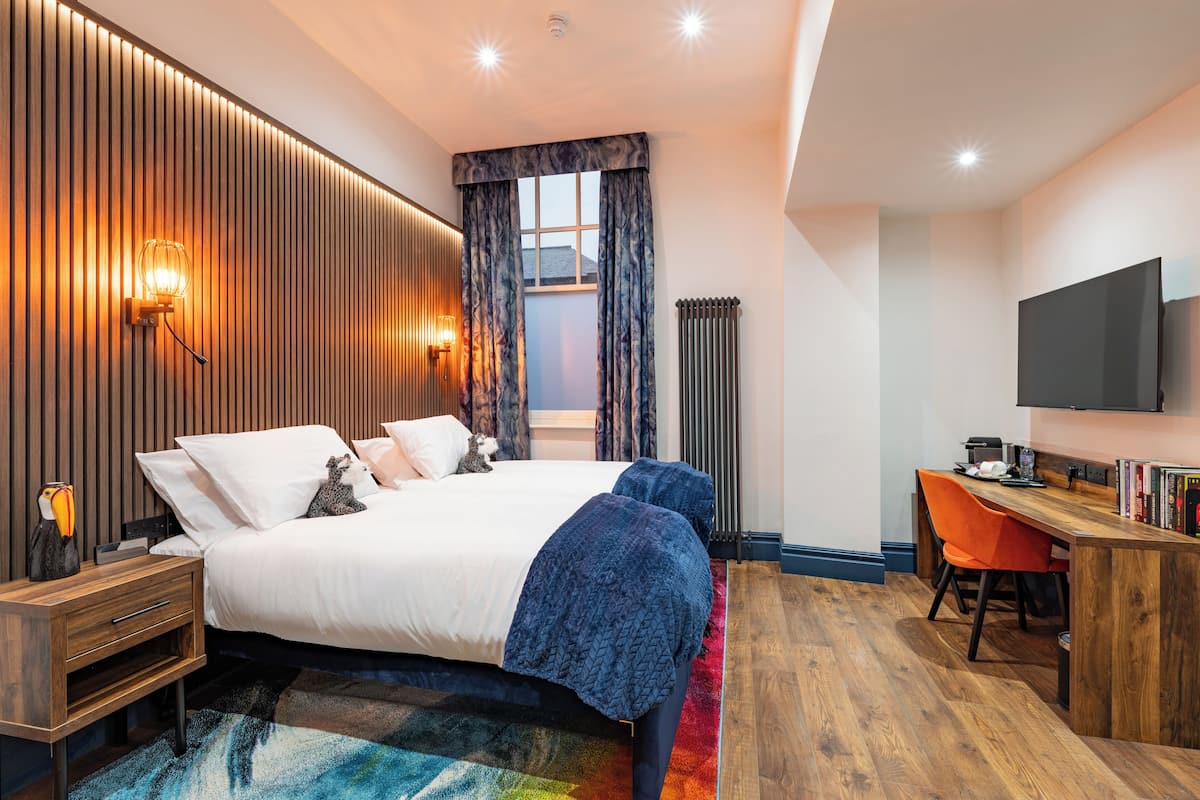 Una habitación de hotel moderna con una cama grande, un escritorio y un televisor.
