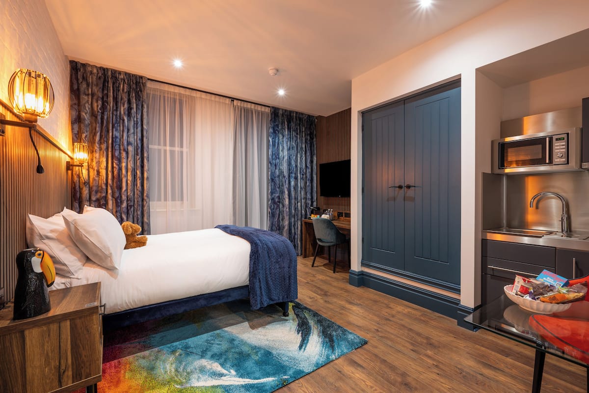 Una habitación de hotel con cama, escritorio, kitchenette y armario.