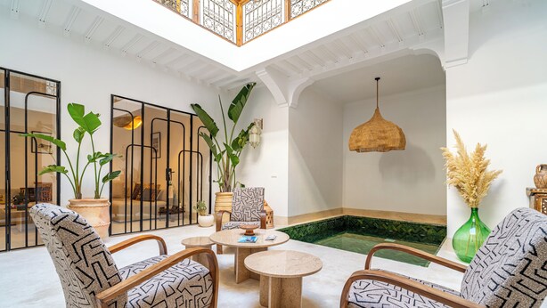 A spacious indoor area with a high ceiling, a seating arrangement with patterned chairs, a small round table, and a decorative hanging light fixture. - Authentic 5-bedroom Riad with swimming pool in the heart of Marrakech's Medina (Marrakech)