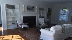 A living room with a fireplace, white furniture, and a wooden floor.