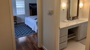 A hotel bathroom with a large mirror, a sink, and a vanity with drawers.