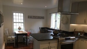 A kitchen with a central island, a stove, and a dining area with chairs and a table.