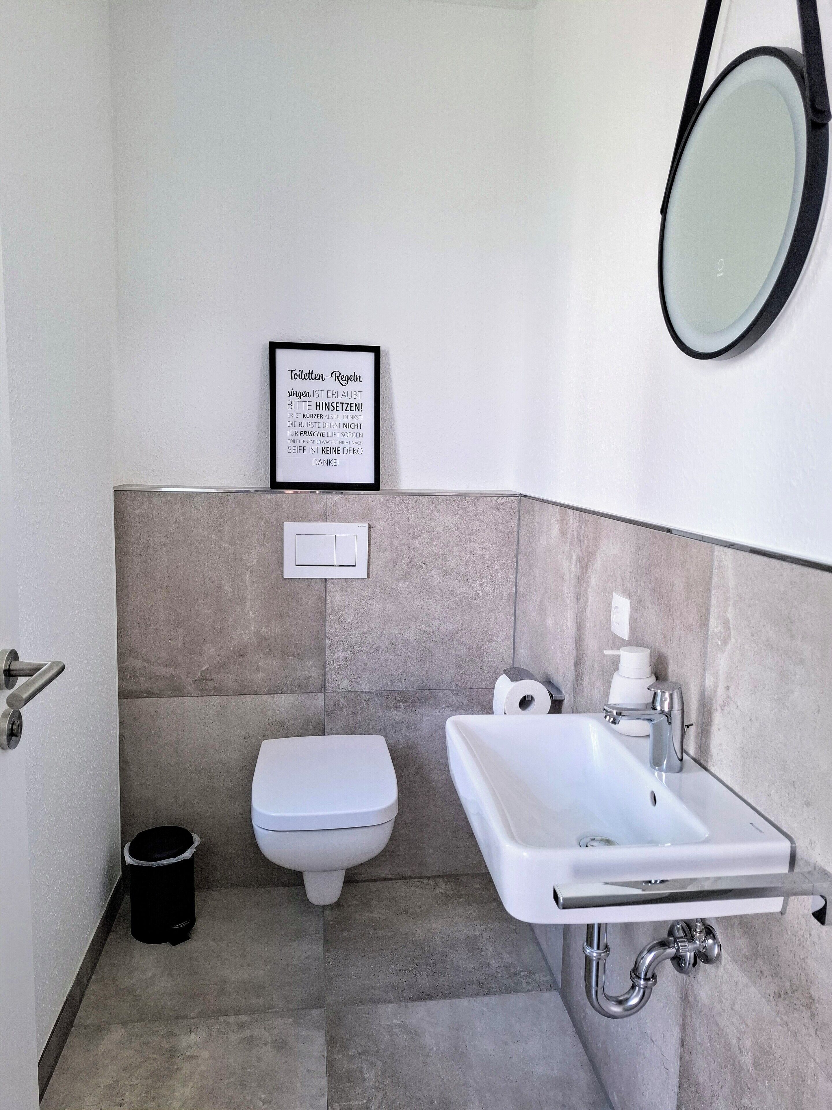Une salle de bain moderne avec des toilettes, un lavabo et une citation encadrée accrochée au mur.