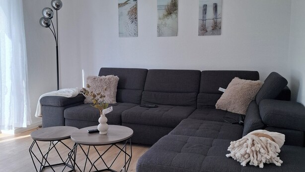 A modern living room with a grey sectional sofa, two round coffee tables, and three wall-mounted artworks. - The beach house, up to 8 people, with garden, 200 meters to the lake (Lembruch)