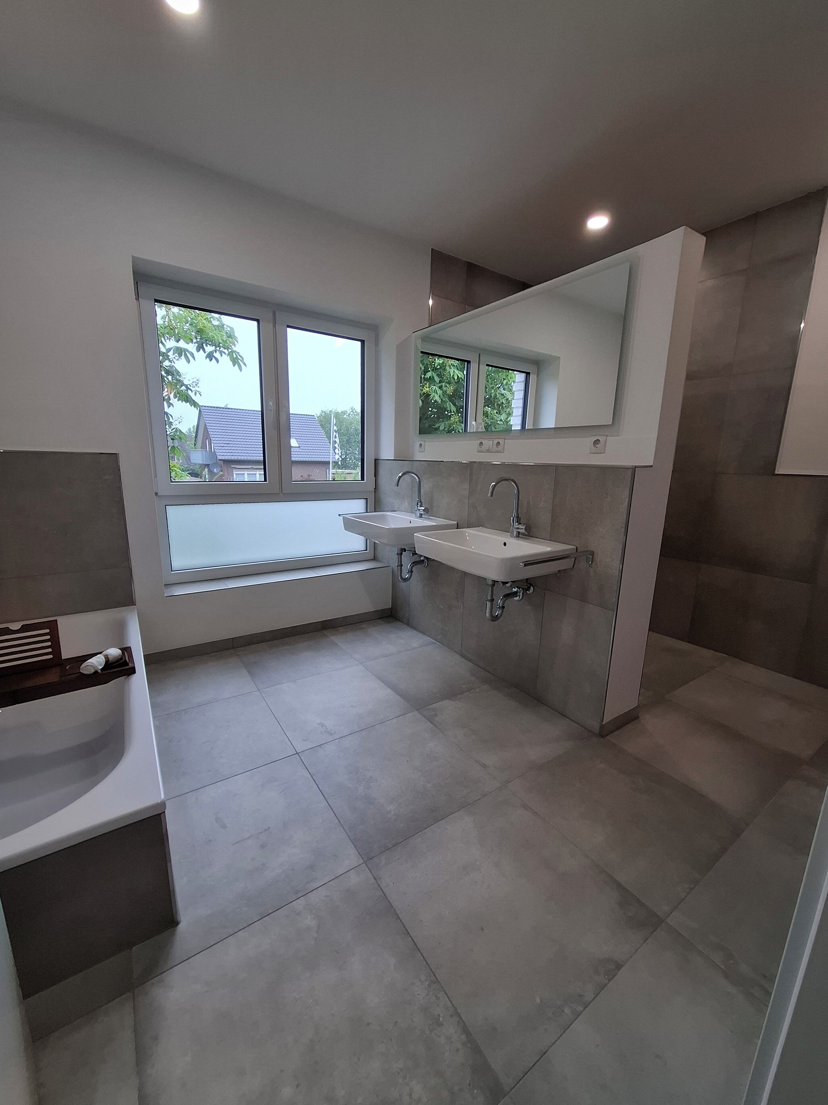 Un baño moderno con dos lavamanos, un espejo grande y un ventanal que proporciona luz natural.