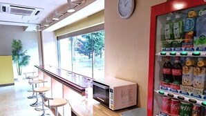 A bar area with stools, a microwave, a clock, and a beverage vending machine.