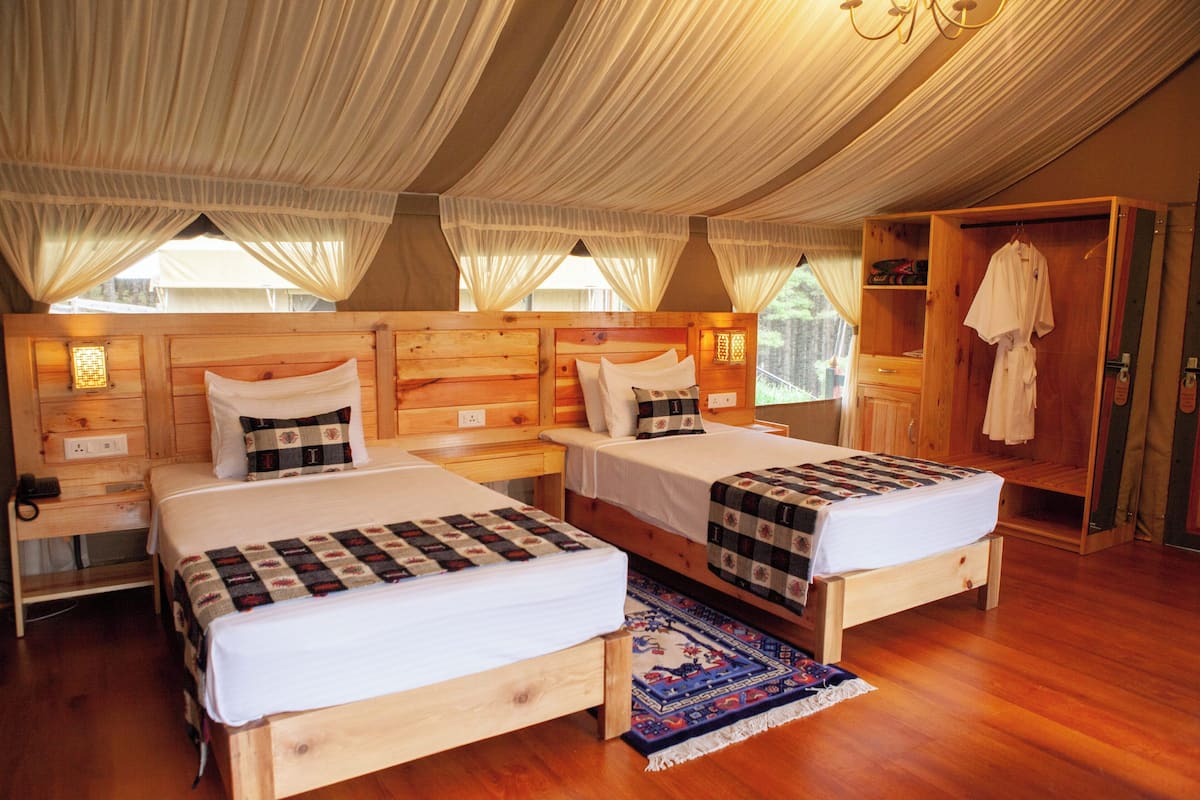 Una habitación de madera con dos camas, un armario y una mesita.