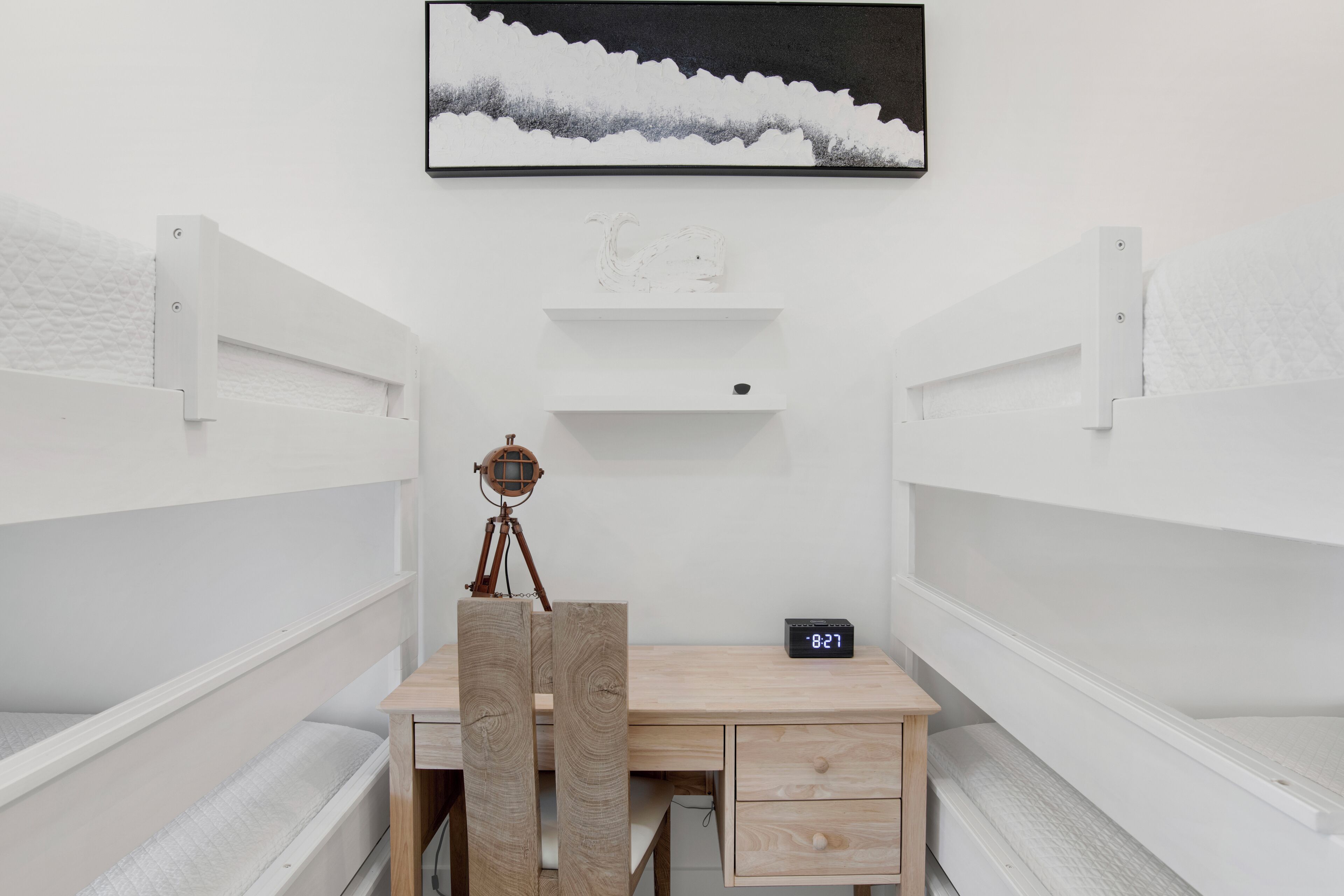 A bunk bed room with a desk and a clock.