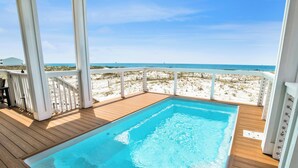 A wooden deck with a swimming pool, white railings, and a view of the beach and ocean. - Gulf Front Luxury | Private Heated, Cooled Pool | Elevator and EV Charging (Gulf Shores)