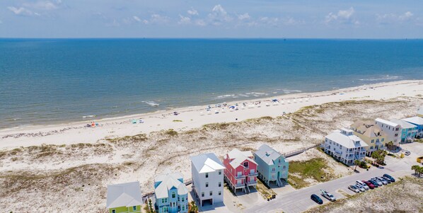 A coastal area with beach houses, a sandy beach, and the ocean.