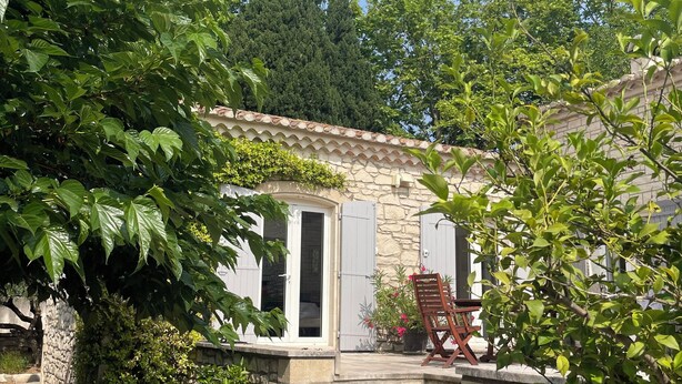 A stone building with a tiled roof, a wooden door, and a set of stone steps leading to a porch.