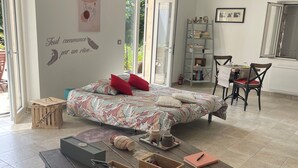 A spacious living area with a large bed, a coffee table with storage, a bookshelf, and a dining area with chairs.