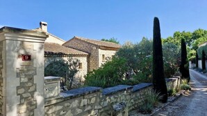 A stone building with a tiled roof, a stone wall, and a narrow gravel path.