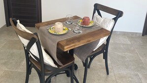 A dining area with a wooden table, two chairs, and a dark door.