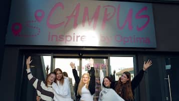 Eine Gruppe von Menschen steht vor einem Gebäude mit einem Schild, auf dem „CAMPUS inspire by Optima“ steht.