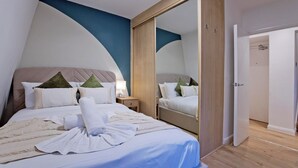 A modern hotel room with a large bed, a wardrobe, and a mirror. - Imperial Queensborough Terrace (London)
