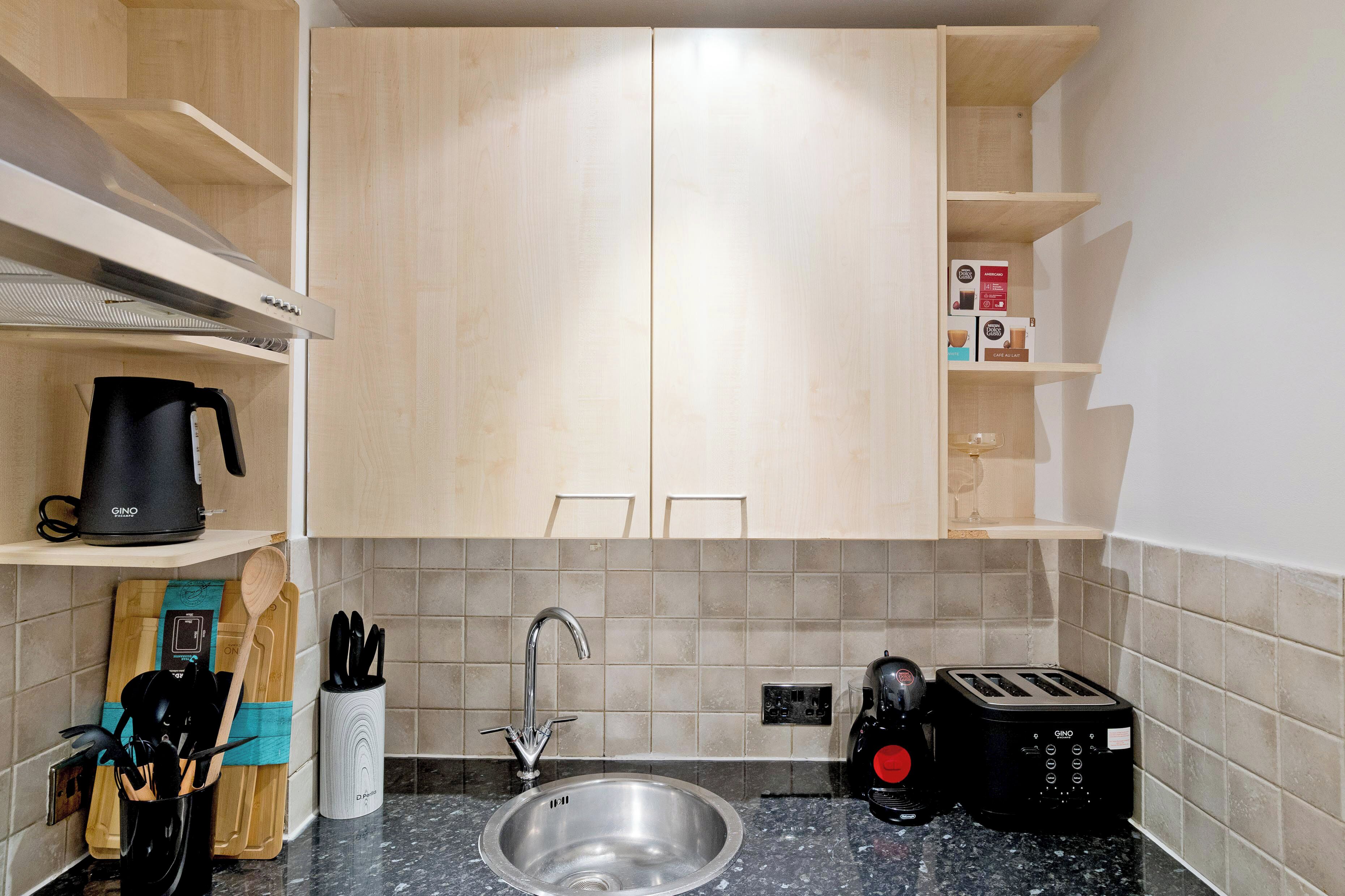 Una cocina moderna con un lavamanos de acero inoxidable, una cafetera negra y un tostador.