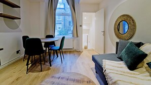 A modern room with a dining table, chairs, a sofa, and a large mirror. - Imperial Queensborough Terrace (London)