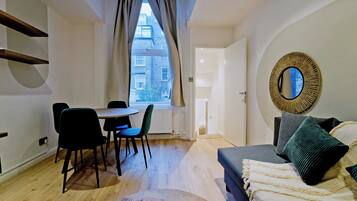 A modern room with a dining table, chairs, a sofa, and a large mirror.