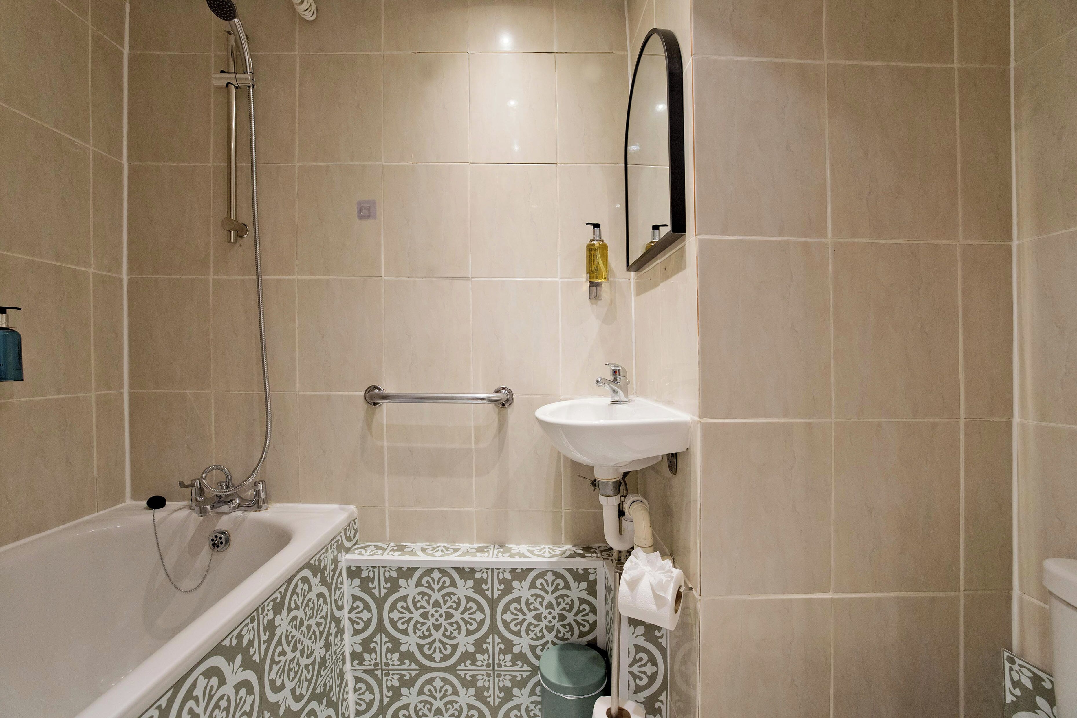 A bathroom with a bathtub, a sink, a mirror, and a toilet.