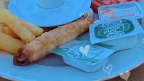 Ein Teller mit verschiedenen Speisen, darunter frittierte Gerichte, eine weiße Soße und frisches Gemüse.