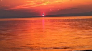 Ein Sonnenuntergang über ruhigem Wasser, mit deutlich erkennbarer Horizontlinie.