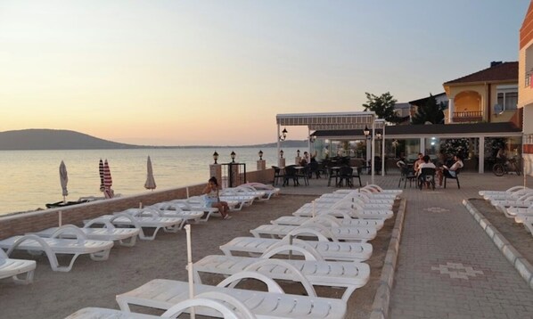Ein Strandcafé mit Liegestühlen und Sonnenschirmen mit Blick aufs Meer.