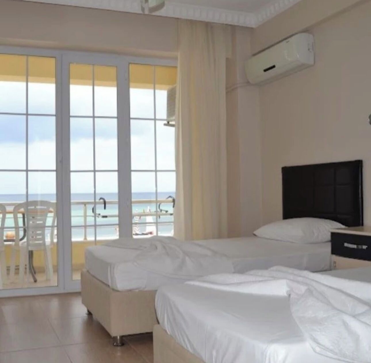 A hotel room with two beds, a TV, and a view of the beach.