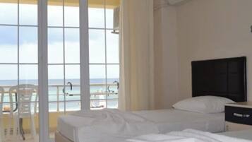 A hotel room with two beds, a TV, and a view of the beach.