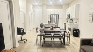 Een moderne keuken met witte kastjes, een centraal eiland en een eethoek met een houten tafel en stoelen.