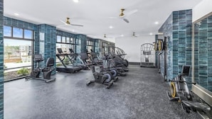 Een fitnessruimte met loopbanden, hometrainers en roeiapparaten.