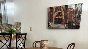 Un coin repas comprenant une table ronde en bois, quatre chaises et un vase décoratif.