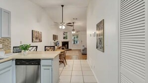 Une cuisine moderne équipée d’un lave-vaisselle, d’un plan de travail en bois et de ventilateurs de plafond.