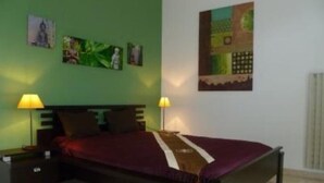 Une chambre à coucher avec un lit, deux tables de chevet et deux lampes fixées au mur.