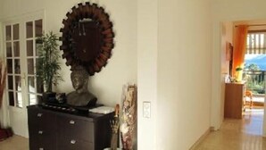 Un couloir avec une commode en bois foncé, une grande horloge décorative et un vase contenant une plante.