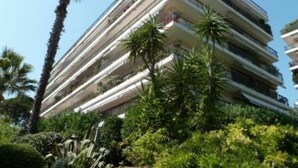 Un hôtel à plusieurs étages doté de balcons, entouré d’une végétation luxuriante et de palmiers.