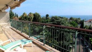 Un balcon avec vue sur la mer, équipé de chaises longues et d’une rambarde.