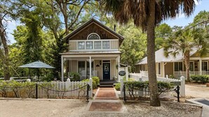 A two-story building with a porch, a sign indicating 'The Lion's Den B&B', and a gravel driveway. - Winslow Hatch House - Steinhatchee Landing Resort (Steinhatchee)