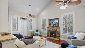 A spacious living room with a fireplace, a ceiling fan, and a television mounted on the wall. - Winslow Hatch House - Steinhatchee Landing Resort (Steinhatchee)