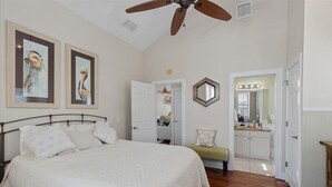 A bedroom with a bed, ceiling fan, and two framed pictures on the wall. - Winslow Hatch House - Steinhatchee Landing Resort (Steinhatchee)