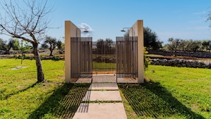 A modern gate with vertical slats and a concrete pathway leading through it. - Ker Rail Villa With Pool by Wonderful Italy (Ostuni)