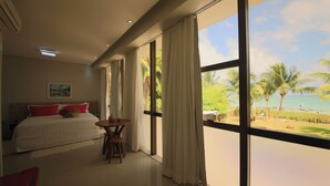 A bedroom with a bed, a table, and a view of a beach. - Obi Exclusive Pousada (Maragogi)